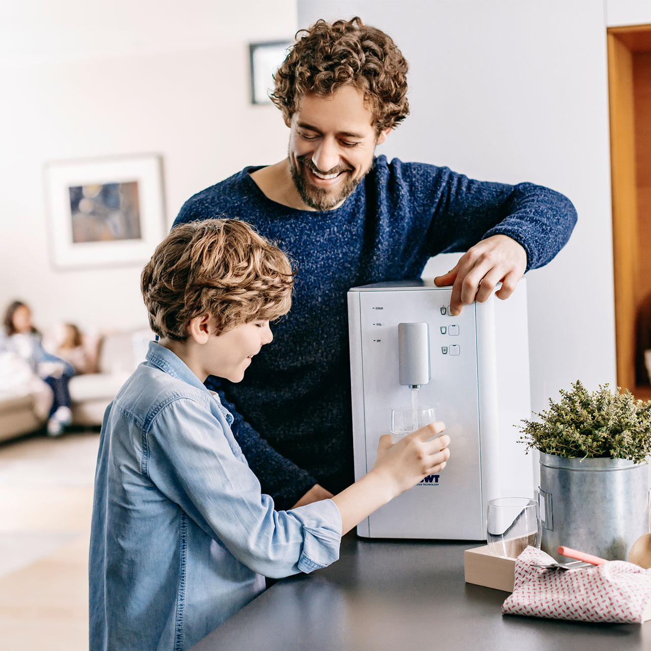 Ein Herr und ein Junge bedienen einen AQA drink Wasserspender